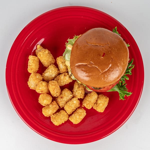 Cheers Sports Eatery burger with lettuce, tomato, and tater tots on a red plate.