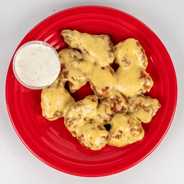 Cheers Sports Eatery's boneless wings covered in a creamy yellow sauce, with a side of ranch.